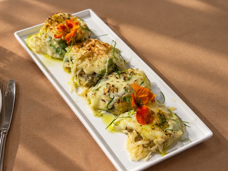 Canapés de alho-poró gratinados com flor comestível em travessa branca